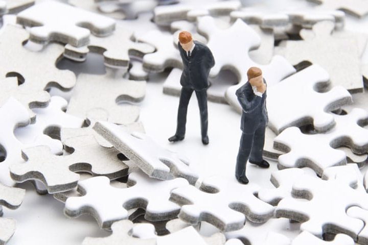 2 figurine men searching for something on the puzzle pieces